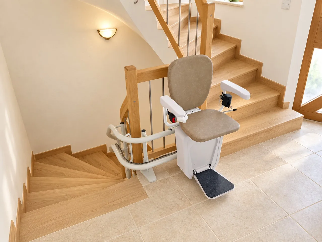 Sitzlift mit hellem Sitz und Fußplatte an einer gewendelten Holztreppe.